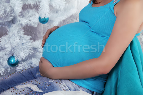 Pregnant woman touching her belly with hands over Xmas tree deco Stock photo © Victoria_Andreas
