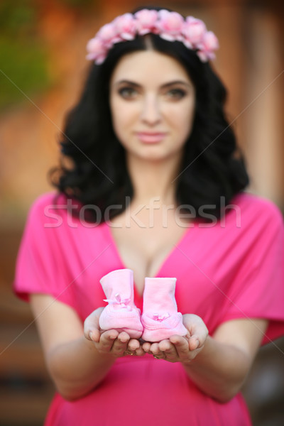 Stock photo: Small shoes for the unborn baby in the hand of pregnant woman is