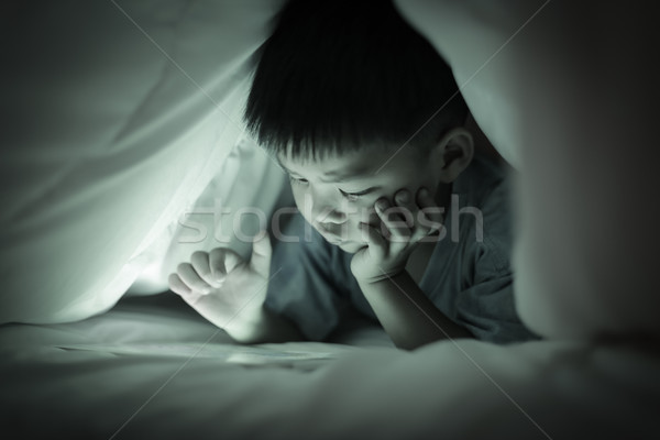 Boy watching online screen tablet, under duvet.  Stock photo © vinnstock