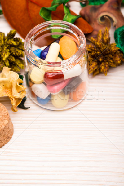 Various pills and capsules in glass container with green Stock photo © viperfzk