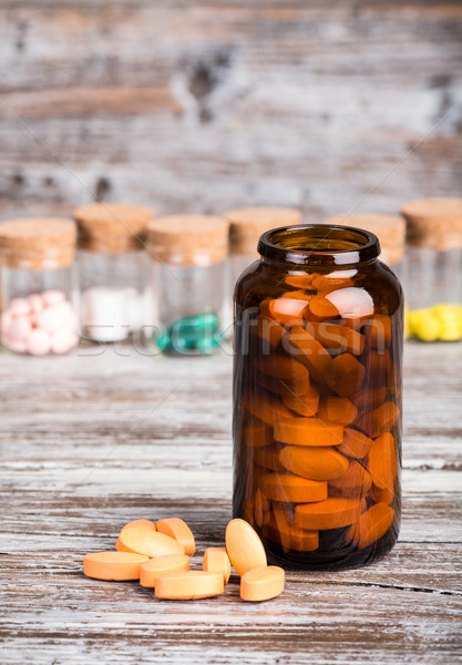 Pills in glass container with other pills on wooden table Stock photo © viperfzk