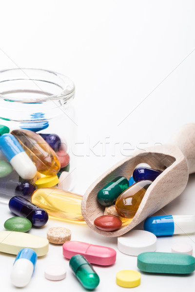 Color pills in glass container and wooden dispencer portrait Stock photo © viperfzk