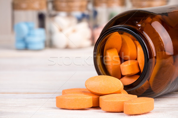 Orange pills in glass container with medicines in back Stock photo © viperfzk