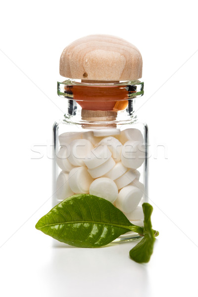 White pills in glass container with wooden top and green leaf Stock photo © viperfzk