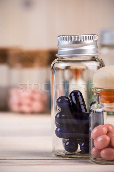 Blue capsules and pink pills in glass containers Stock photo © viperfzk