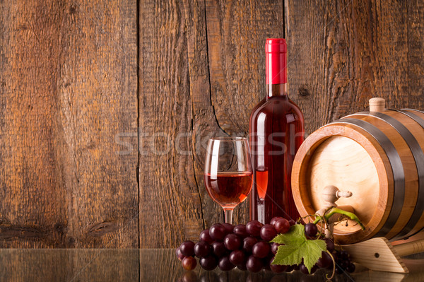 Glass of rose wine with bottle barrel grapes and wooden backgrou Stock photo © viperfzk
