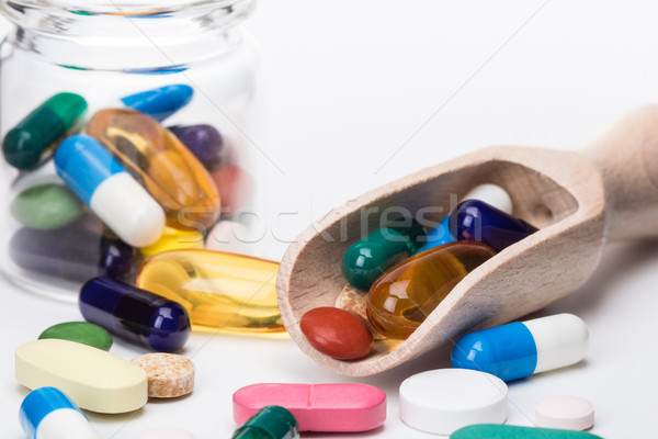 Color pills in glass container and wooden dispencer Stock photo © viperfzk