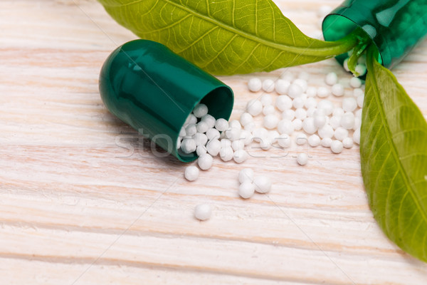 Open capsule with small white specs and green leaf Stock photo © viperfzk