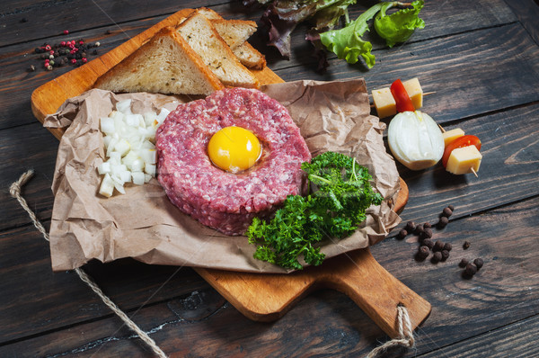 Beef tartare with bread and fresh onion on a wooden background Stock photo © voloshin311