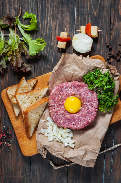 Beef tartare with bread and fresh onion on a wooden background Stock photo © voloshin311