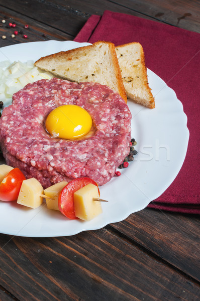 Beef tartare with bread and fresh onion on a wooden background. Stock photo © voloshin311