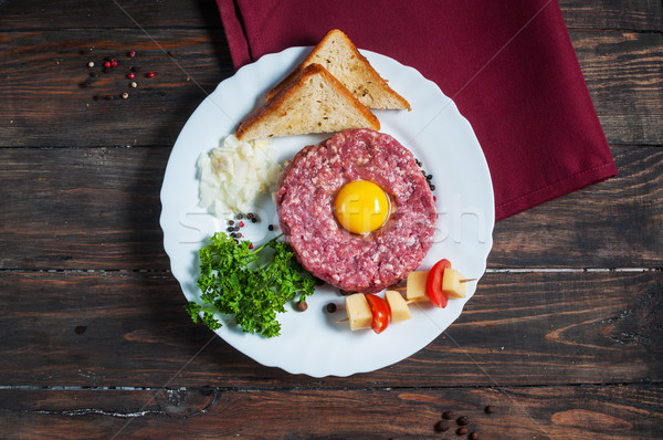 Beef tartare with bread and fresh onion on a wooden background Stock photo © voloshin311