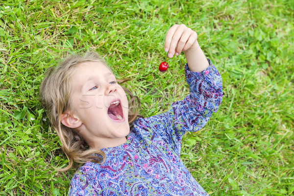 girl lying on the grass with cherry Stock photo © vwalakte