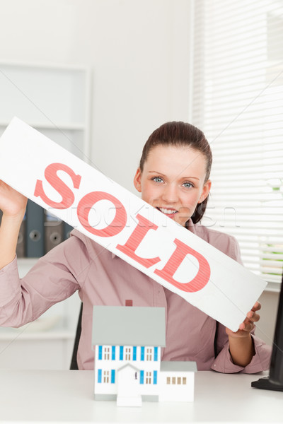 A businesswoman is holding a sold sign above a miniature house Stock photo © wavebreak_media