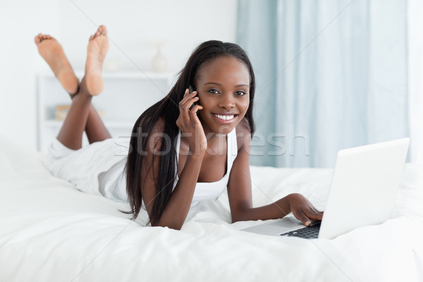 Szczęśliwy kobieta notebooka rozmowa telefoniczna sypialni Zdjęcia stock © wavebreak_media