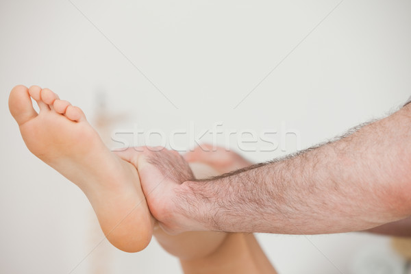 Stock photo: Close-up of a physiotherapist moving a leg in a room