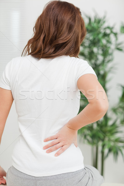 Brunette sitting while massaging her painful back in a room Stock photo © wavebreak_media