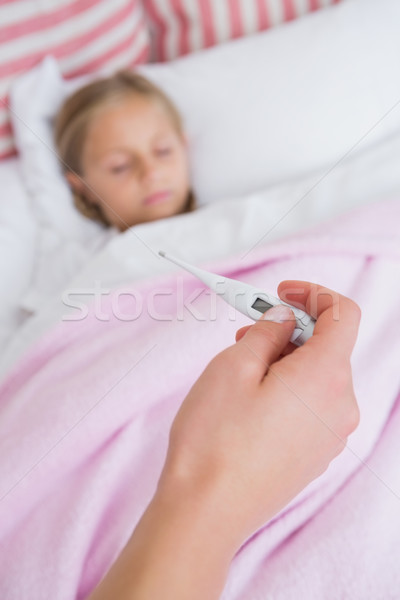 Stock photo: Mother taking the temperature of sick daughter