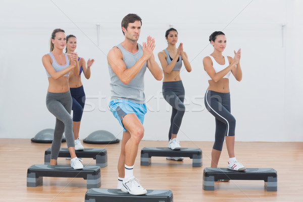 Instructor with fitness class performing step aerobics exercise Stock photo © wavebreak_media