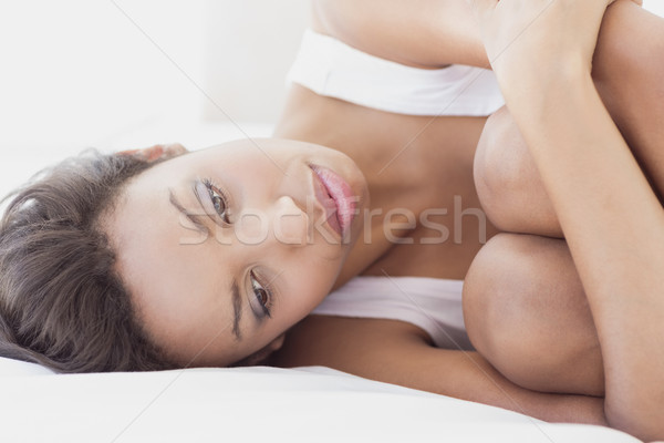 Unhappy brunette lying on bed hugging her knees Stock photo © wavebreak_media
