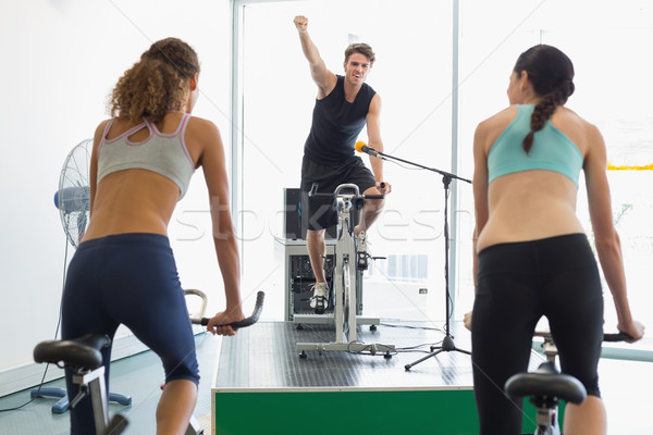 Stock photo: Fit women doing a spin class with enthusiatic instructor