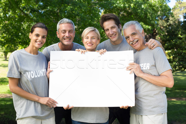 Happy volunteer family holding a blank  Stock photo © wavebreak_media