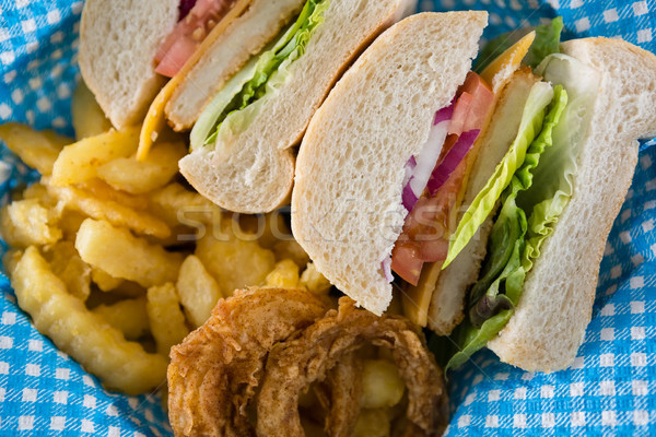 Stock photo: Close up of sliced burger with French fries and onion rings