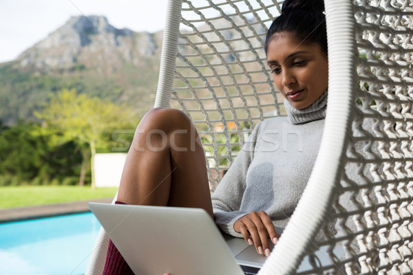 Mulher usando laptop balançar cadeira relaxante água Foto stock © wavebreak_media