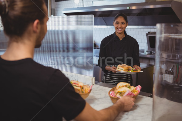 Waitress giving plate with food to coworker in cafe Stock photo © wavebreak_media