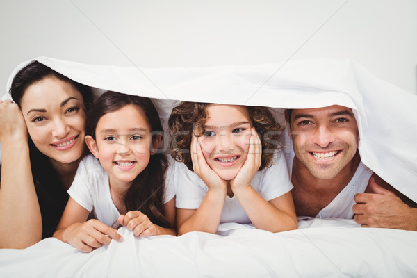 Cheerful family below blanket on bed Stock photo © wavebreak_media