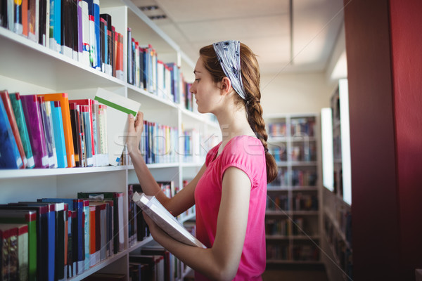 Schoolgirl selecting book from book shelf in library Stock photo © wavebreak_media