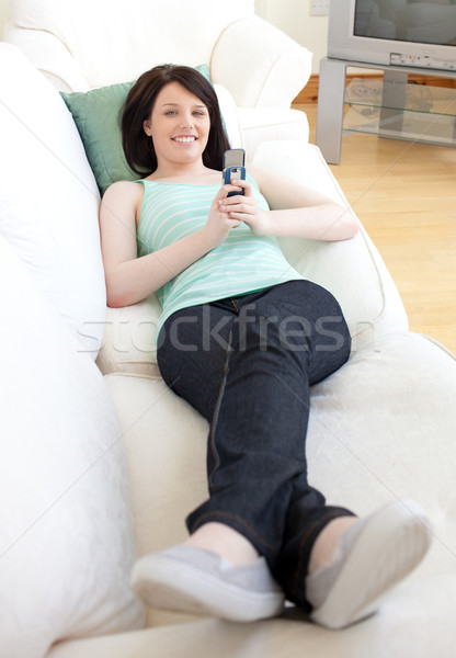 Jolly woman sending a text lying on a sofa Stock photo © wavebreak_media