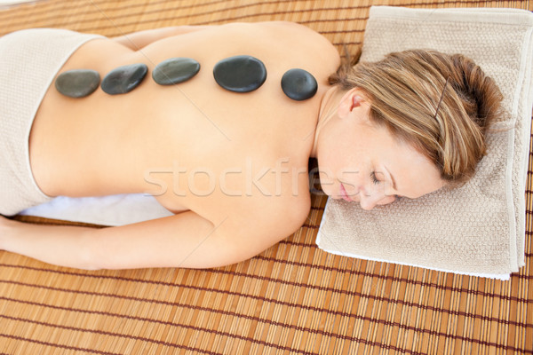 Stock photo: Resting caucasian woman lying on a massage table with hot stones in a health spa