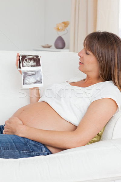 Close up of a pregnant woman looking at her baby's ultrasound scan in her living room Stock photo © wavebreak_media