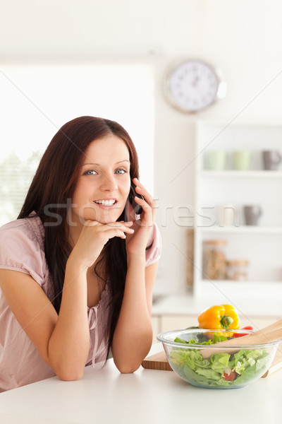 Stock photo: A woman is telephoning at a table with a salad on it