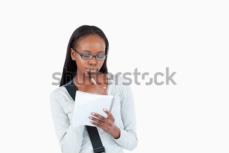 Stock photo: Young woman with glasses reading her notes against a white background