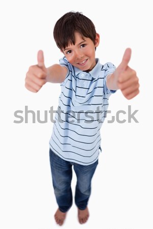 Stock photo: Portrait of a boy smiling at the camera with the thumbs up against a white background