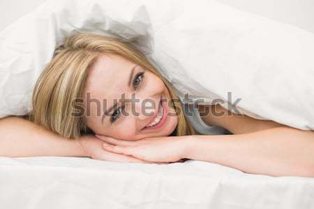 Femeie zambitoare lies pat cap pernă faţă Imagine de stoc © wavebreak_media