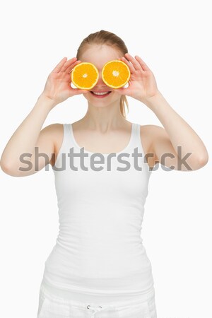 Blond-haired woman placing oranges on her eyes against white background Stock photo © wavebreak_media