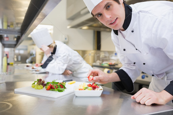 Stock photo: Happy chef preparing a fruit salad in the kitchen