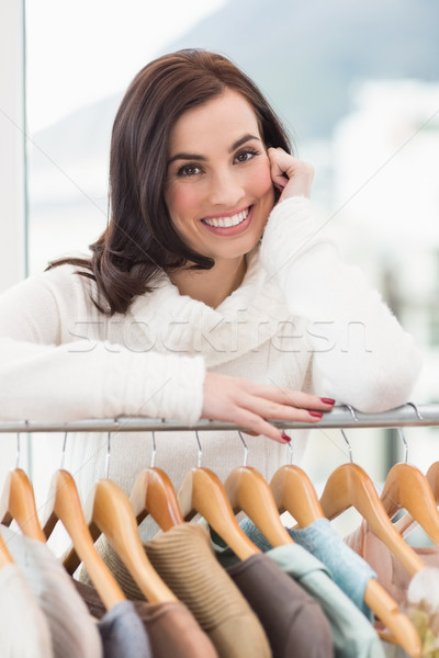 Beauty brunette smiling at camera by clothes rail Stock photo © wavebreak_media
