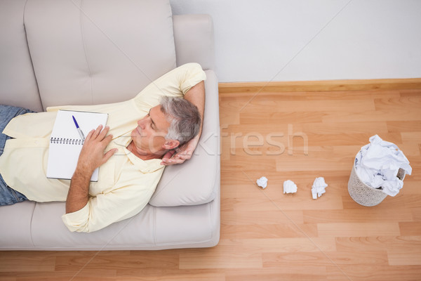 Man lying on couch with crumpled papers Stock photo © wavebreak_media