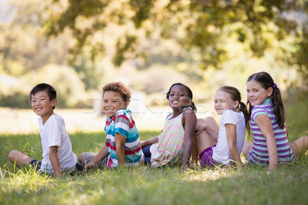 Stock photo: Smiling friends sitting on grass at campsit