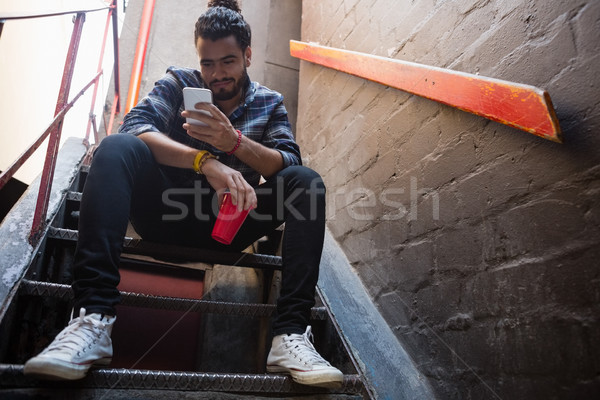 Man using mobile phone while having drink on staircase Stock photo © wavebreak_media