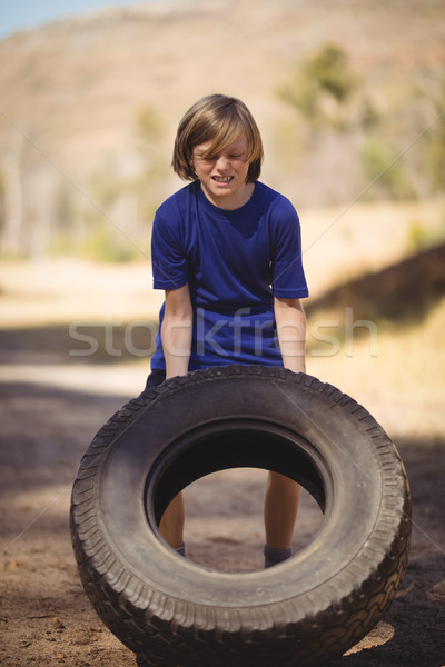 Determined girl exercising with huge tyre during obstacle course Stock photo © wavebreak_media