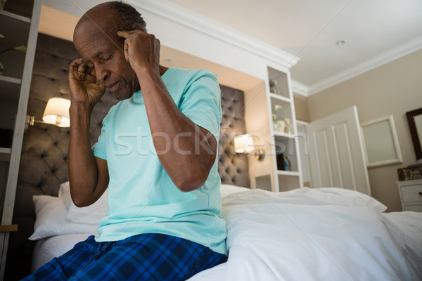 Stock photo: Senior man suffering from headache while sitting on bed