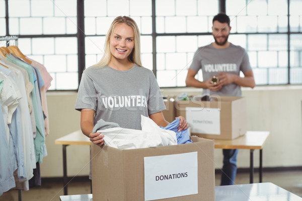 Stock photo: Portrait of woman separating clothes from donation box 