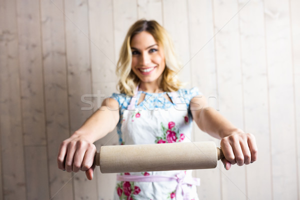 Stock photo: Woman in apron holding a rolling pin against texture background