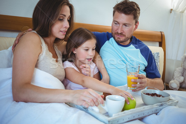 Parents sitting on bed with daughter and having breakfast Stock photo © wavebreak_media