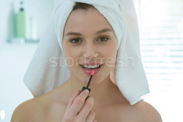 Woman applying lip gloss on her lips in bathroom Stock photo © wavebreak_media